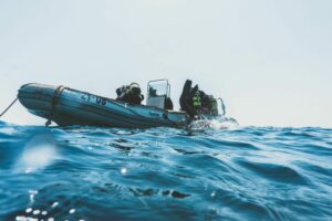 Scuba divers equipped for an ocean dive prepare from an inflatable boat on a sunny day.